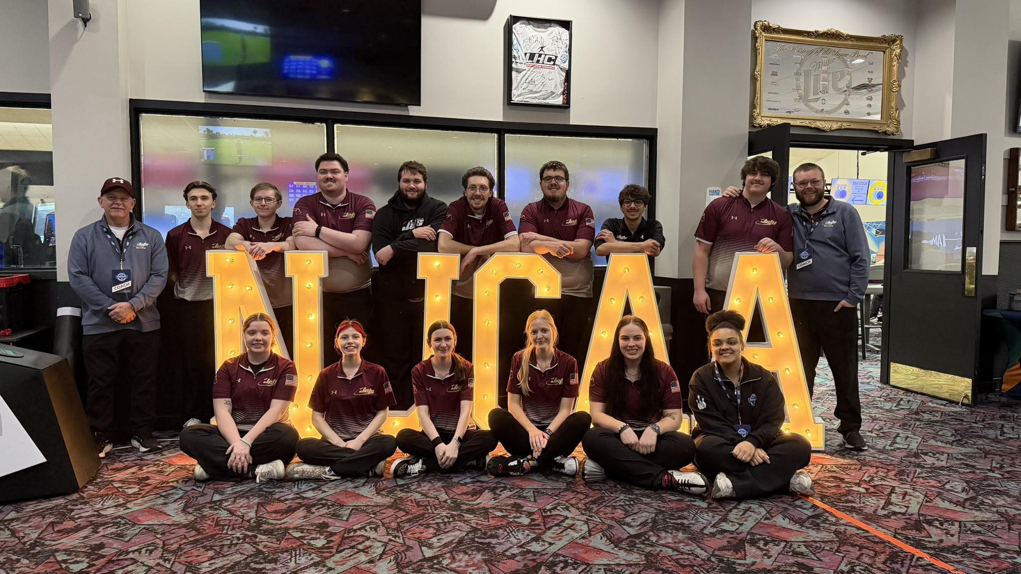 mens and womens bowling team standing in front of NJCAA sign